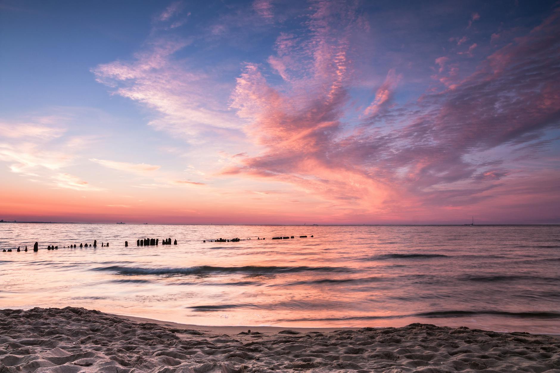 Slow travel nad Bałtykiem: 7 pomysłów na spokojny, ekologiczny urlop Plaża w Gdańsku o zachodzie słońca z różowo-pomarańczowym niebem