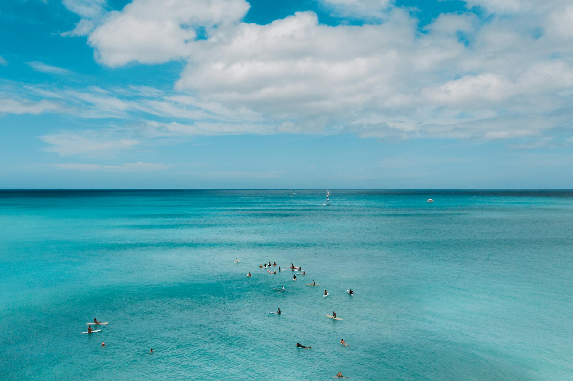Surferzy na spokojnym morzu pod częściowo zachmurzonym niebem