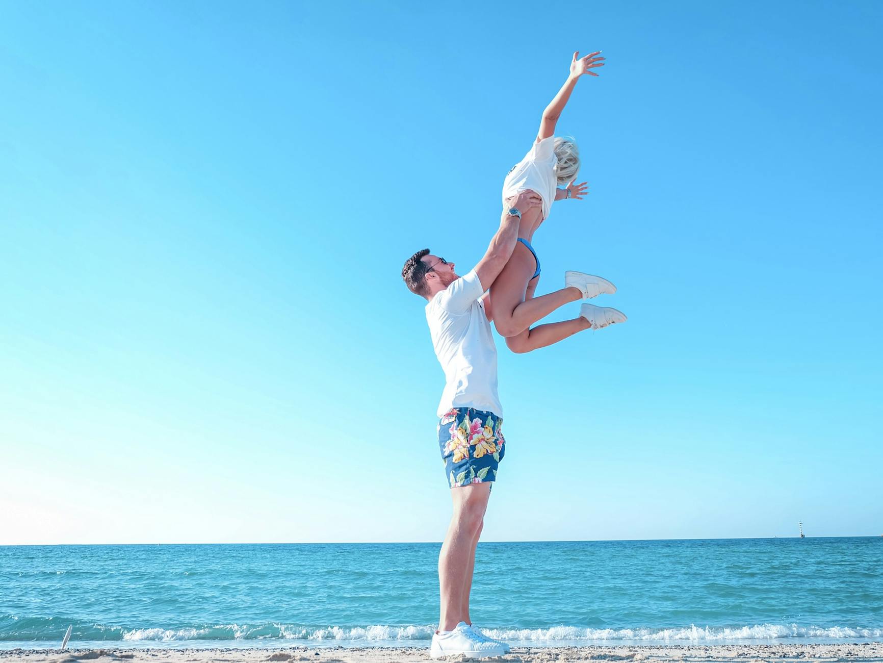Uśmiechnięta para bawi się na plaży nad morzem latem