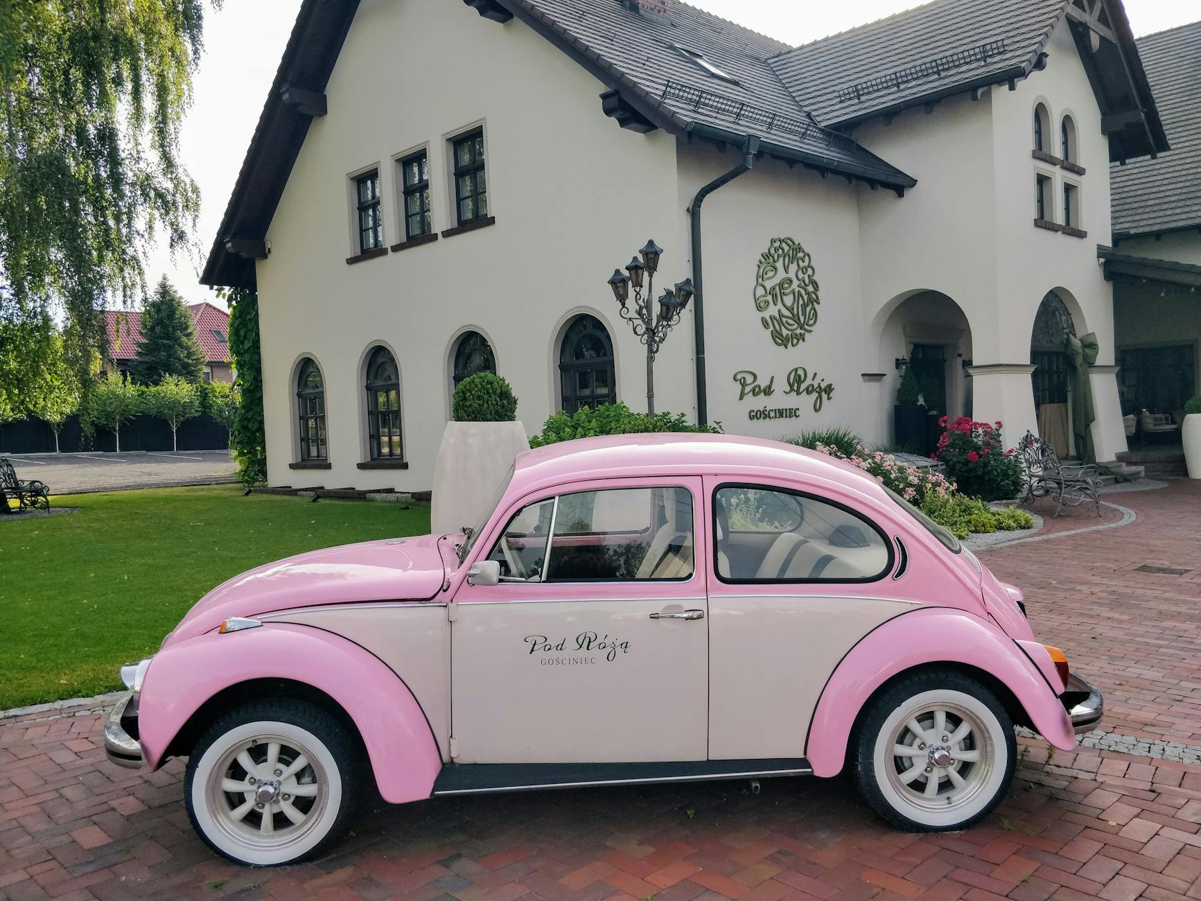 Różowy garbus przed pensjonatem z ogrodem nad morzem