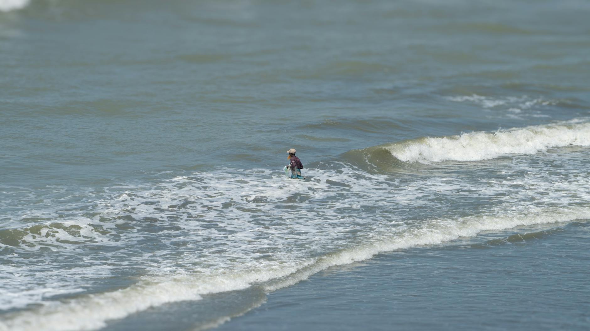 Samotny surfer płynie na fali na spokojnym oceanie pod błękitnym niebem