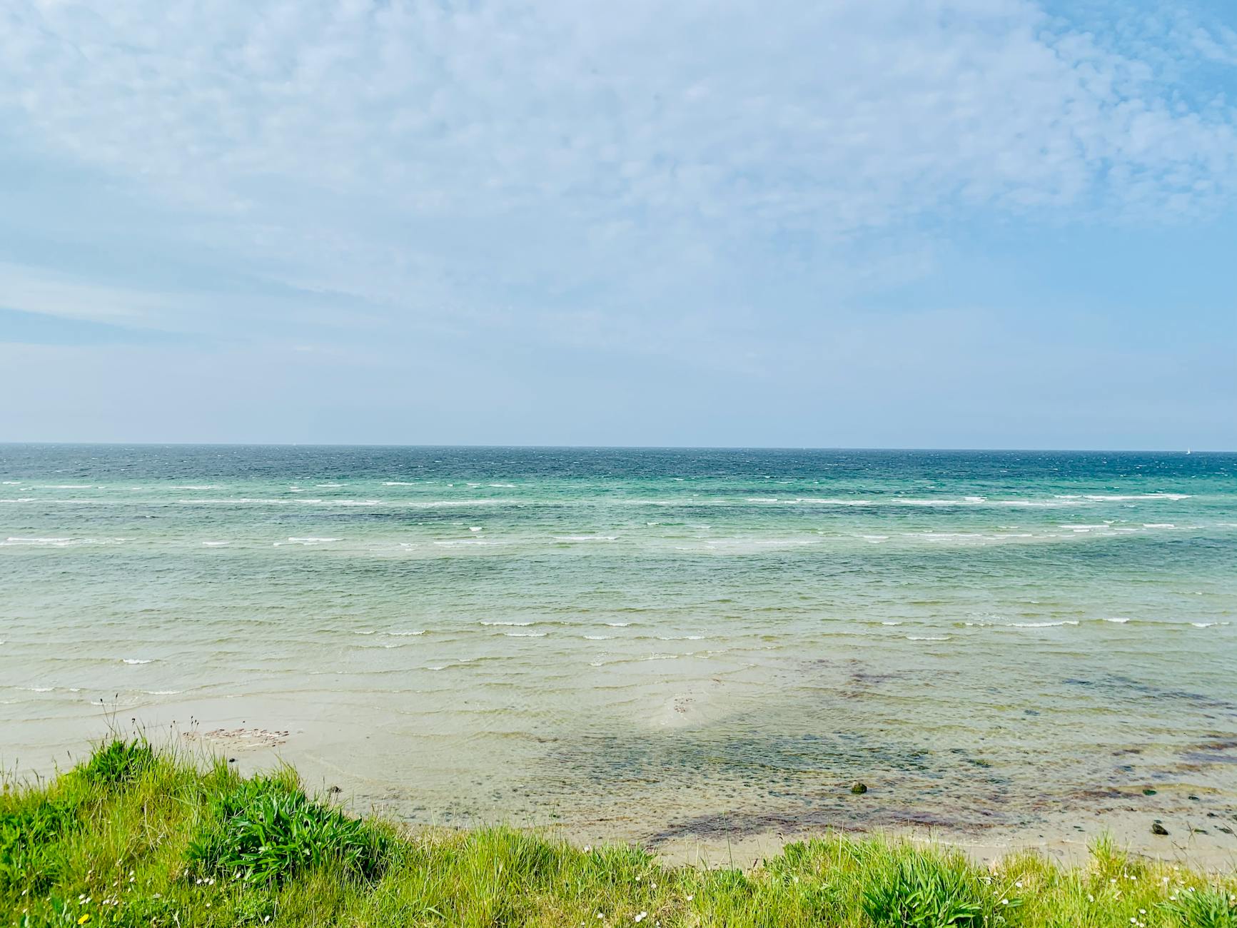 Spokojne fale błękitnego Bałtyku pod lekko zachmurzonym niebem