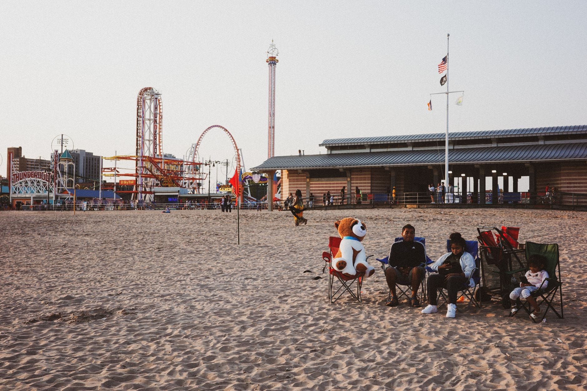 Plaże z darmowymi parkingami: gdzie nad Bałtykiem mniej zapłacisz za dojazd Rodzina odpoczywa na plaży, w tle wesołe miasteczko