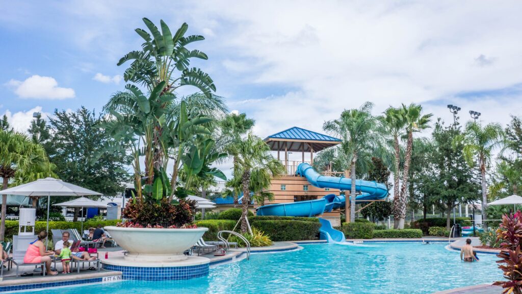 Basen ze zjeżdżalnią wodną i palmami w tropikalnym resorcie